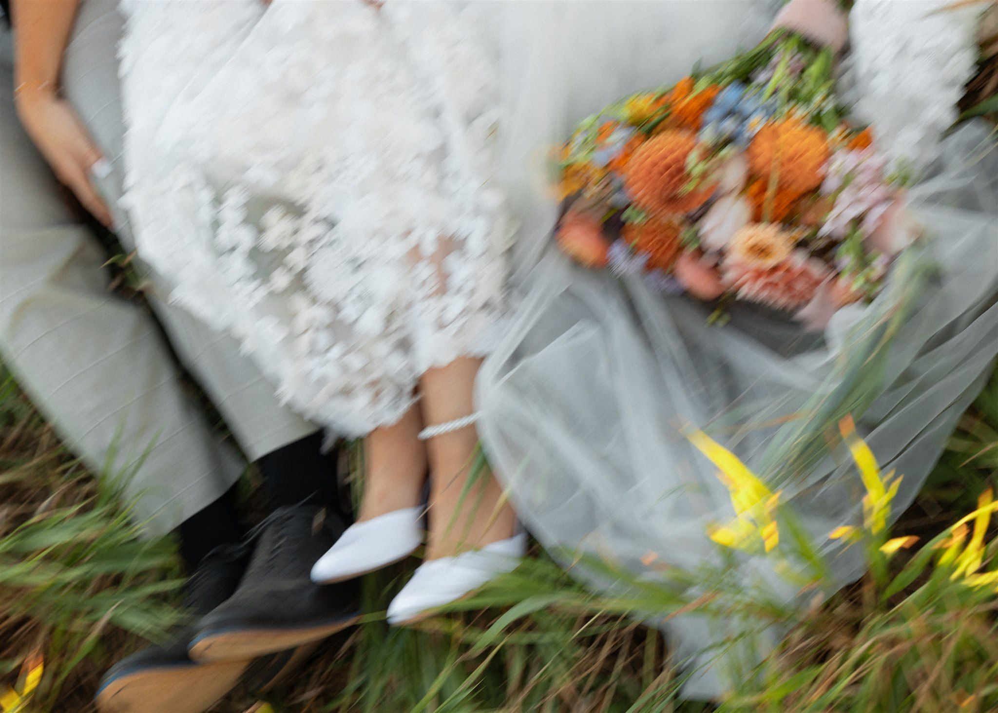 Wedding dress detail with orange and yellow wildflowers in a field.